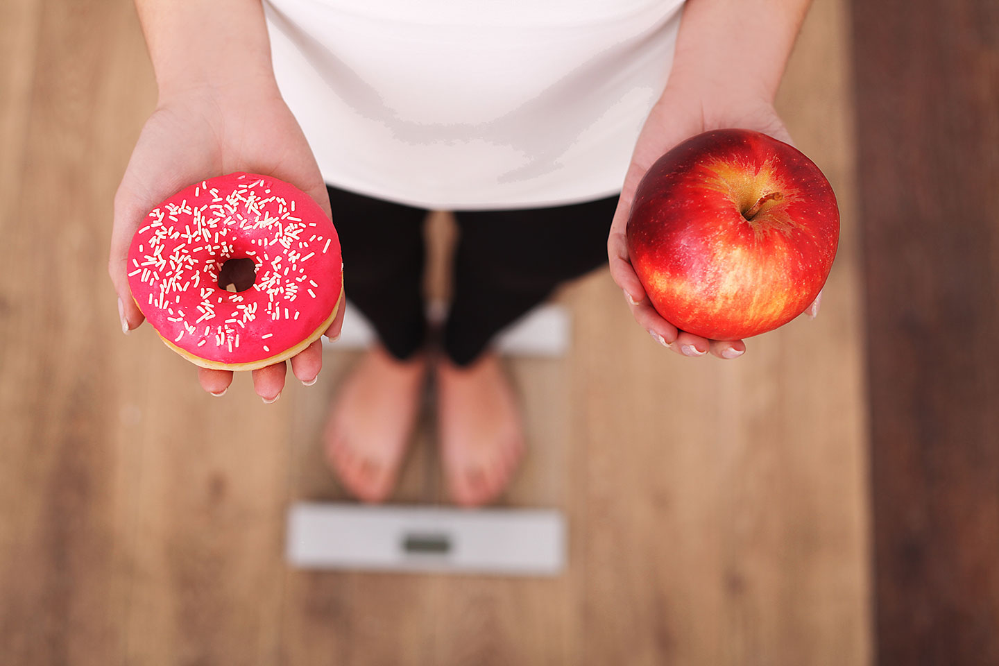 Woman on scale deciding between a donut or an apple